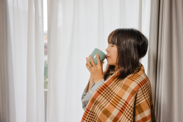 毛布に包まって水を飲む女性